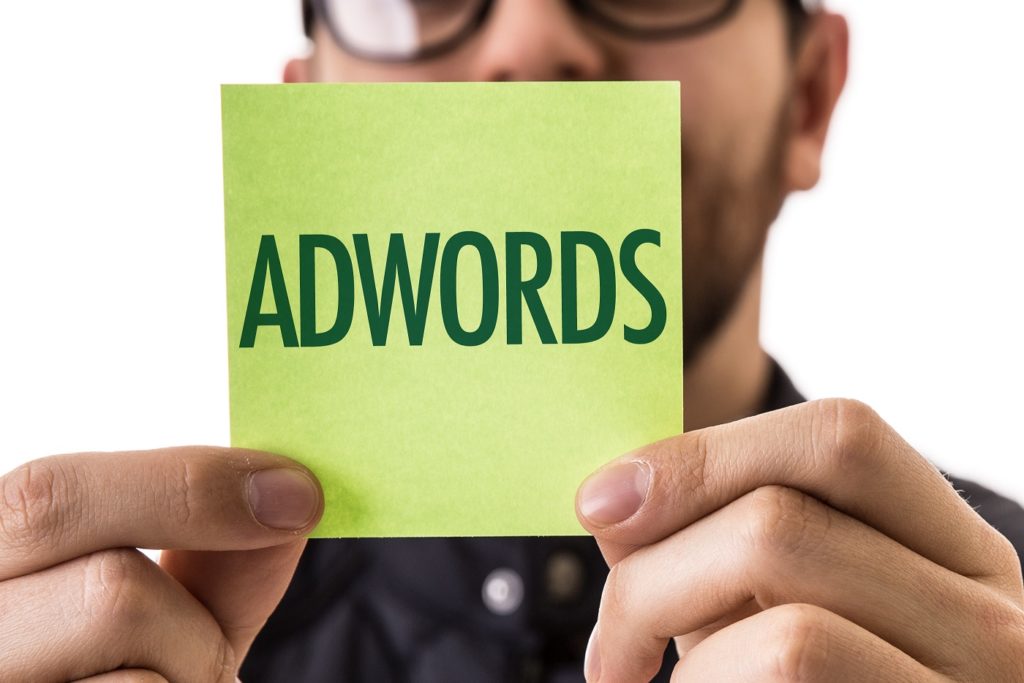 a man holding up a post it note with the word AdWords written on it