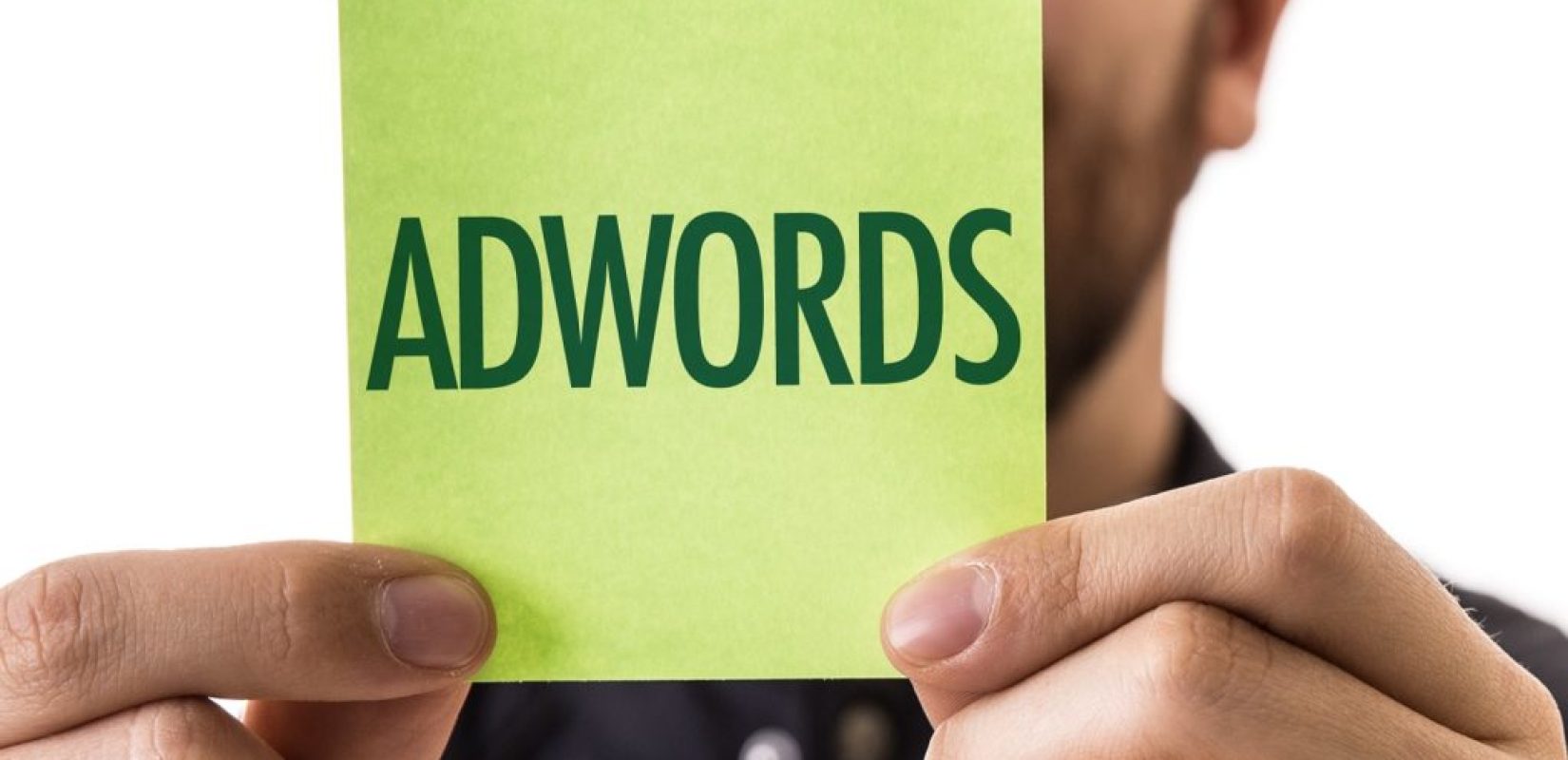 a man holding up a post it note with the word AdWords written on it